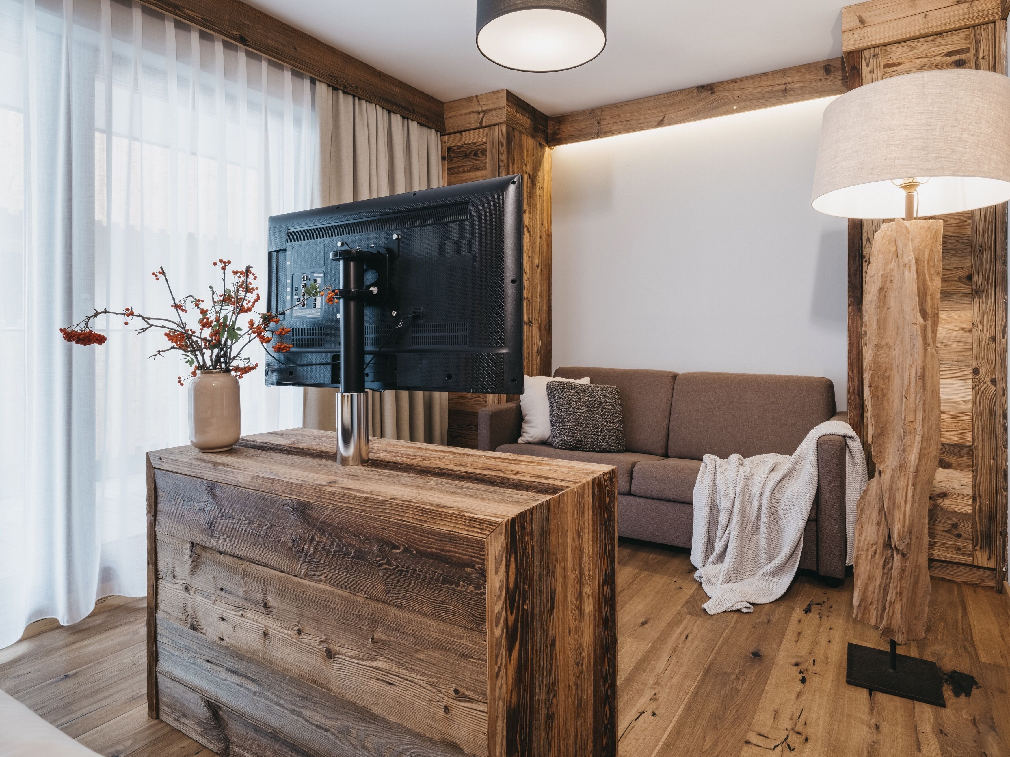 A modern living room with a wooden coffee table, a sofa, and a television mounted on a wooden wall.