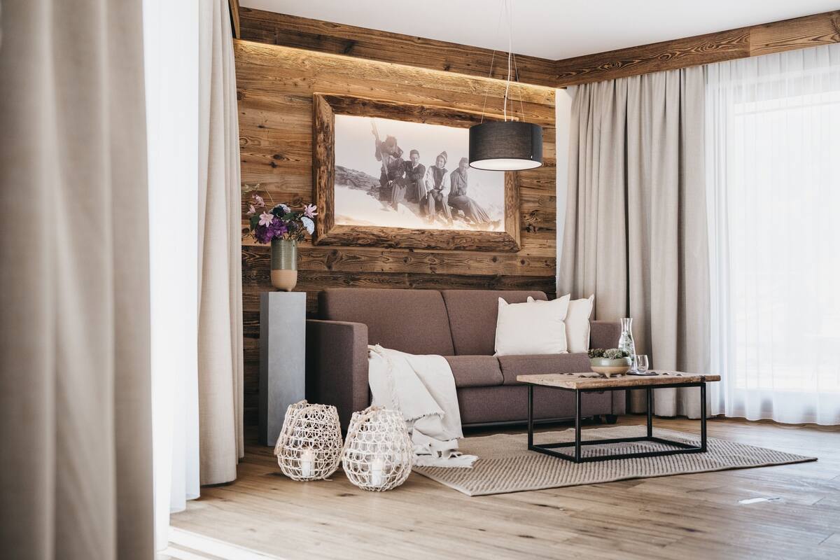 Una sala moderna con una pared de acento de madera, una fotografía blanco y negro enmarcada, un sofá marrón, una mesa de centro y dos faroles decorativos.