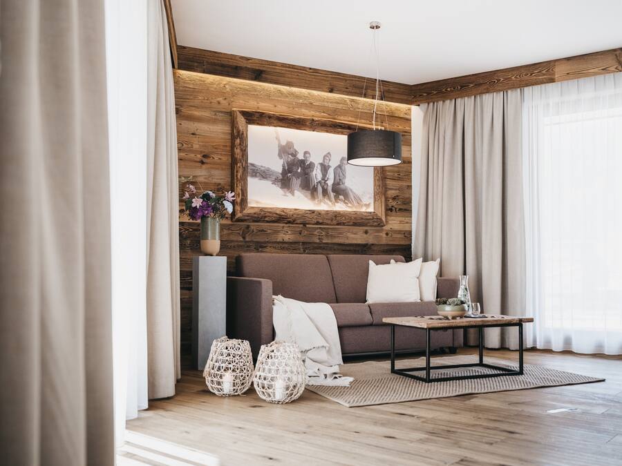 A modern living room with a wooden accent wall, a framed black and white photo, a brown sofa, a coffee table, and two decorative lanterns.