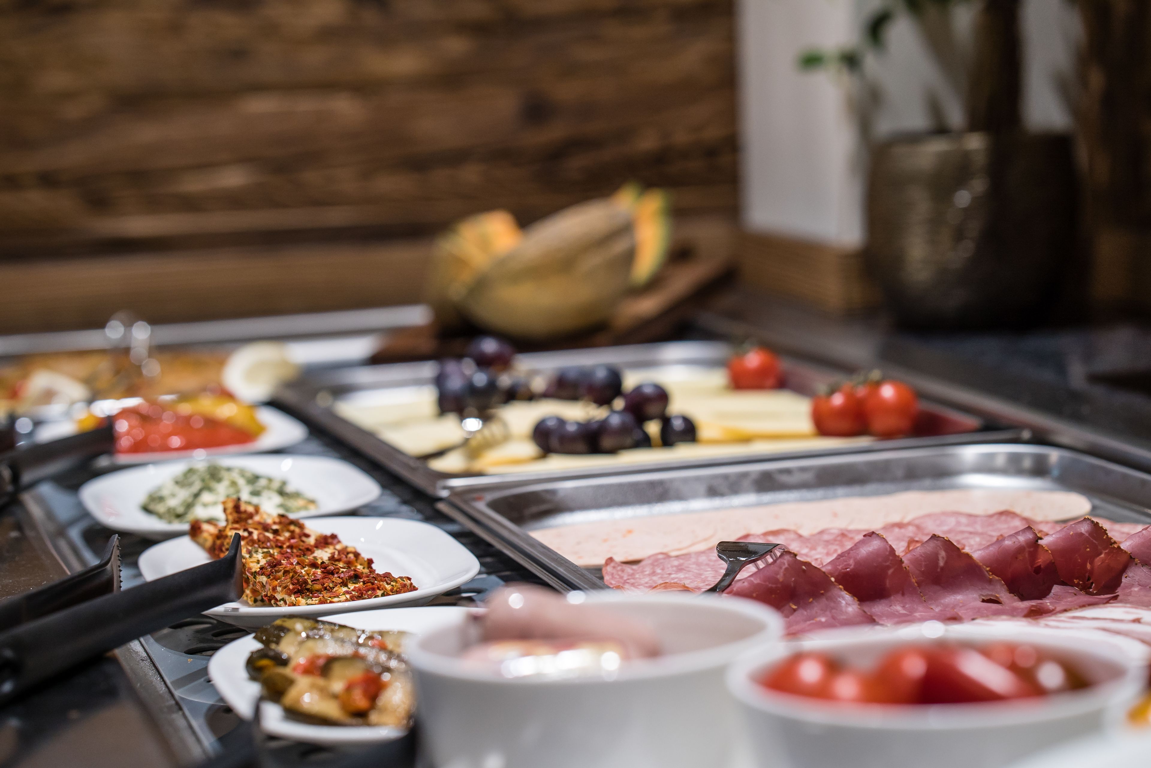 A buffet with various food items including meats, cheeses, and fruits.