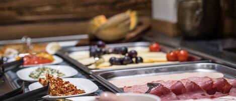 A buffet with various food items including meats, cheeses, and fruits.