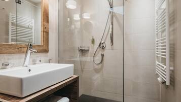 A modern bathroom with a glass-enclosed shower, a white sink, and a wooden vanity.