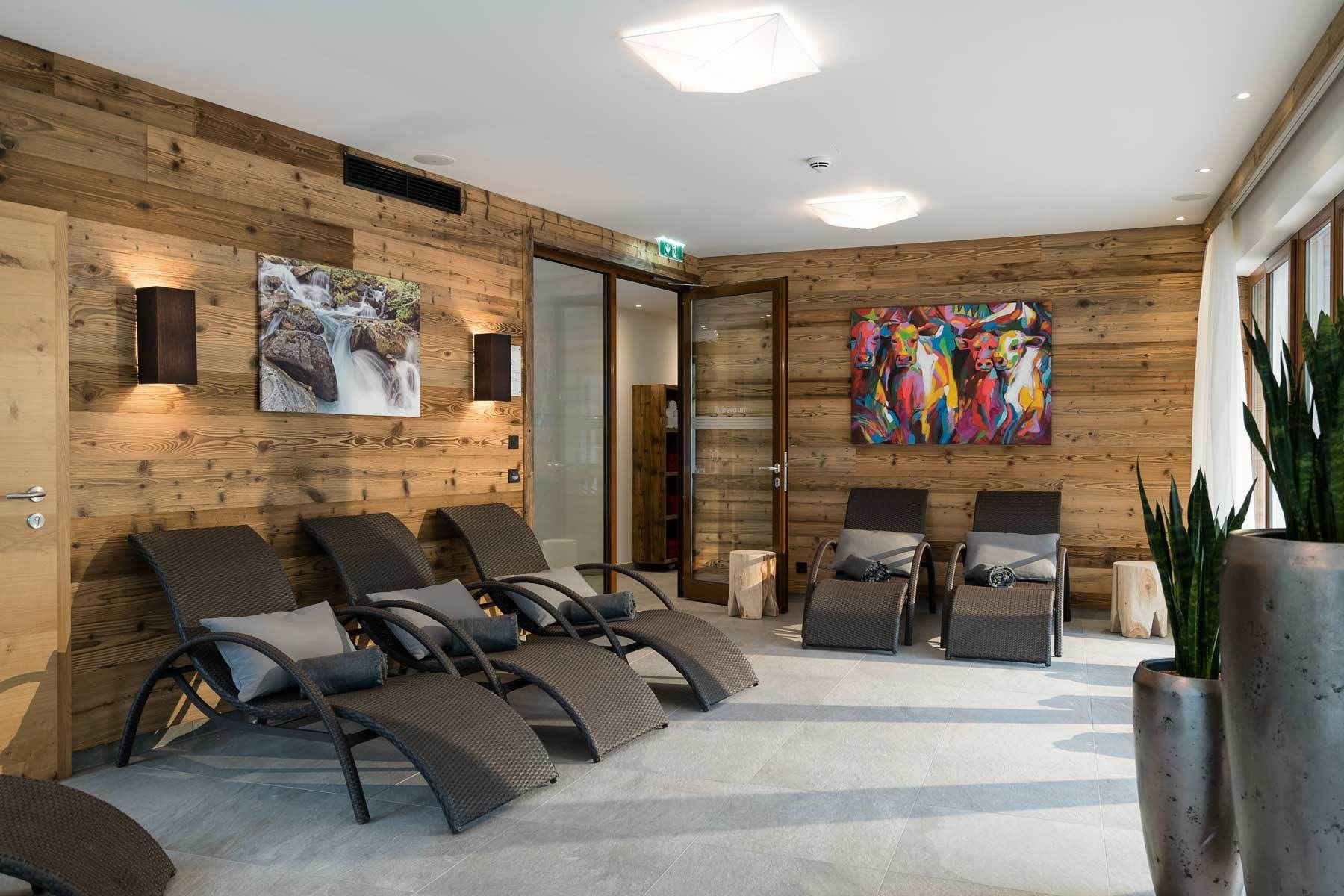 Un espace de détente avec des murs en bois, des fauteuils inclinables, une peinture abstraite aux couleurs vives et une plante en pot.