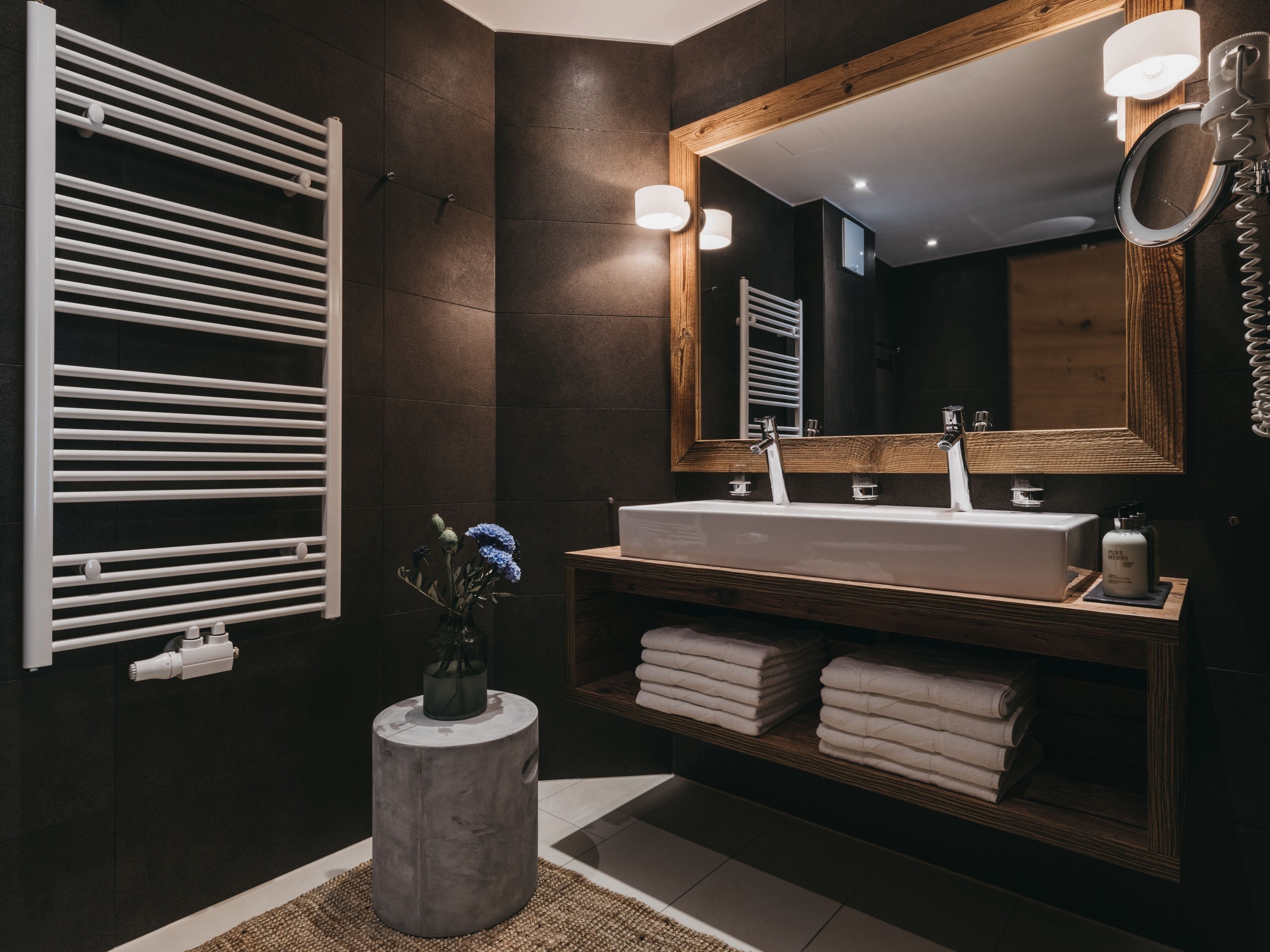 A modern bathroom with a large mirror, two sinks, and a towel rack.