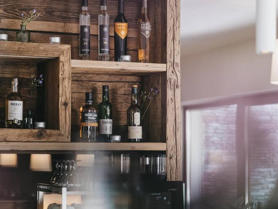 A wooden wine rack with various bottles of wine and spirits.
