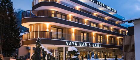 A multi-story hotel with a bar and grill, featuring a modern design with balconies and large windows.
