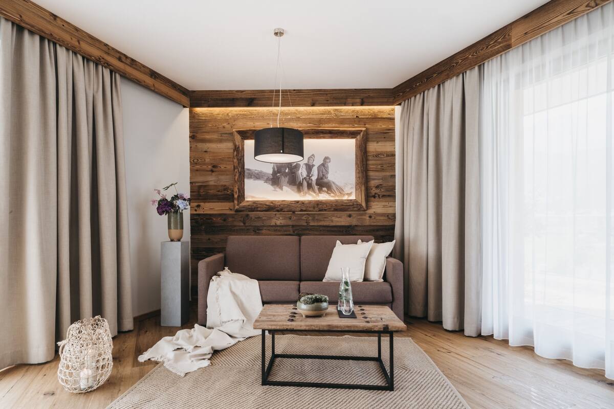 Una sala de estar moderna con una pared de acento de madera, un sofá, una mesa de centro y una lámpara colgante.