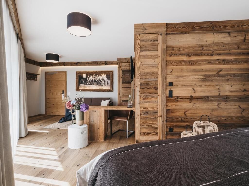 Un dormitorio moderno con una pared de acento de madera, una cama, un escritorio y una silla.