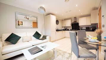 A modern living room with a sofa, coffee table, and dining area with chairs and a glass table.