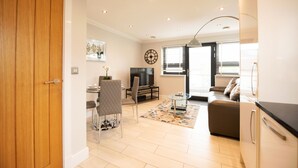 A modern living room with a sofa, a dining table, and a TV. - Malthouse Court (Reading)