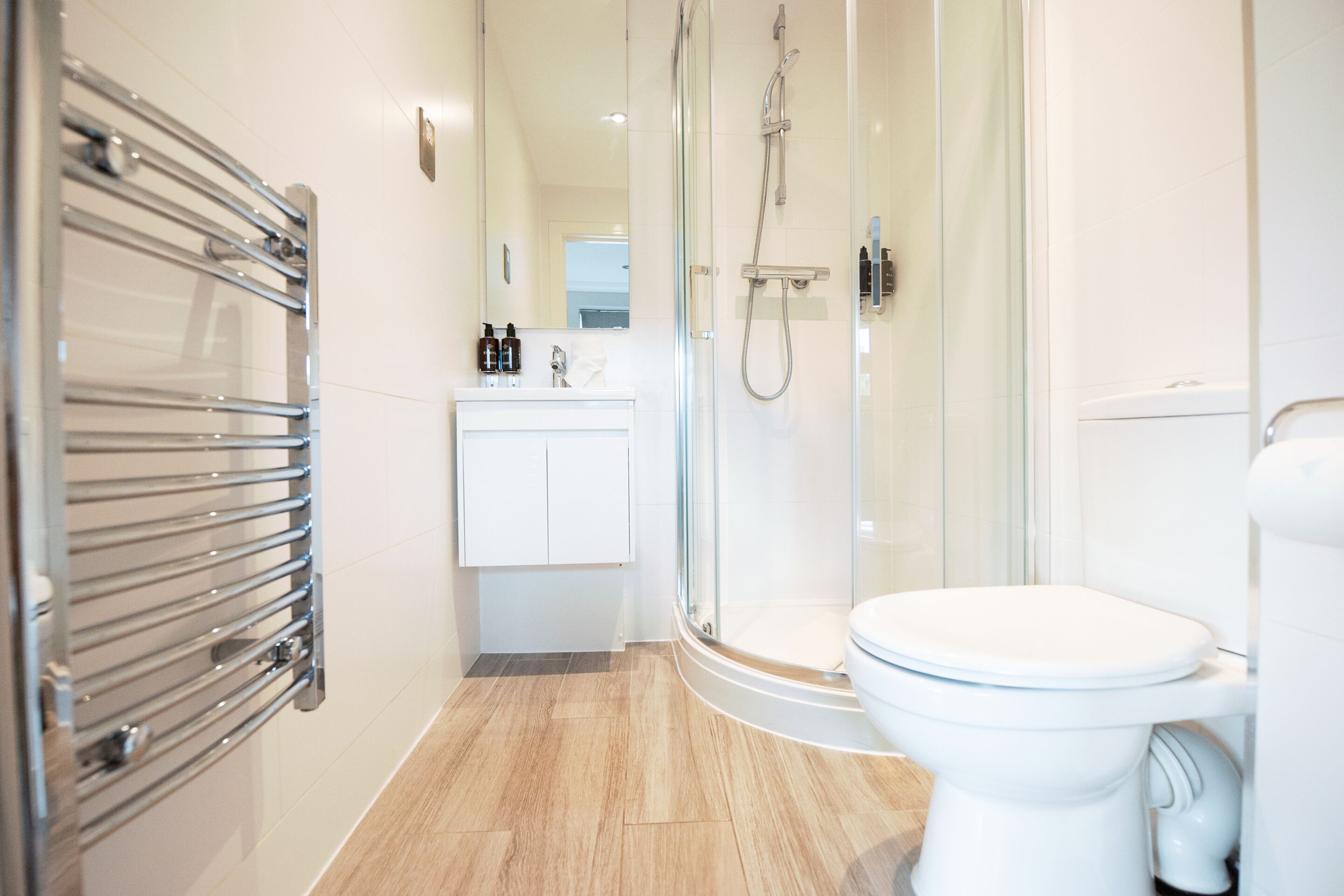 A modern bathroom with a glass shower enclosure, a white toilet, and a built-in sink with a mirror.