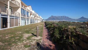 A hotel with multiple balconies overlooking a beach and mountains. - Leisure Bay 306 by CTHA (Cape Town)