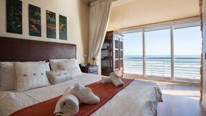 A hotel room with a large bed, a view of the ocean, and artwork on the wall. - Leisure Bay 306 by CTHA (Cape Town)