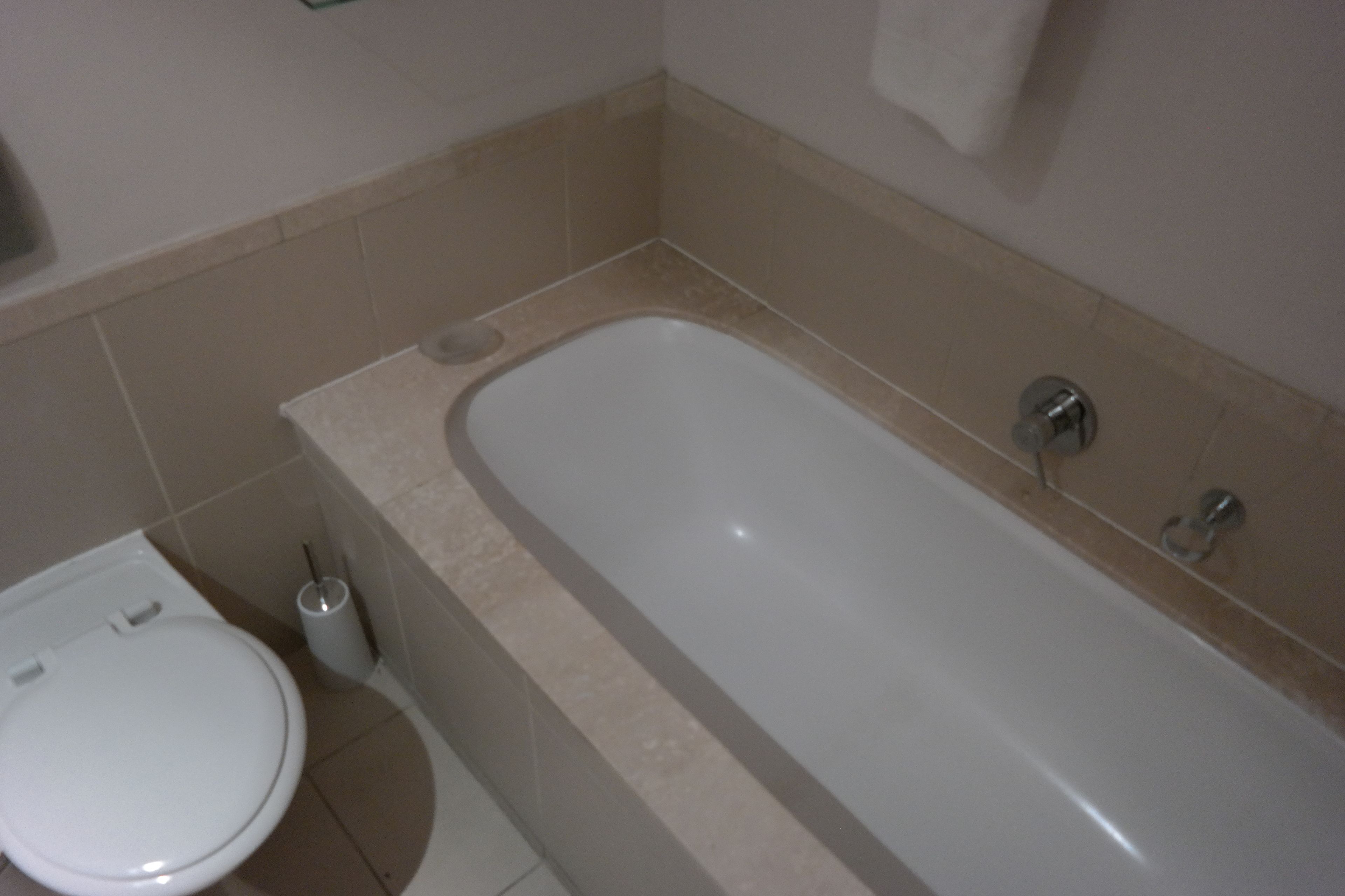 A bathroom with a bathtub, toilet, and a hand dryer.