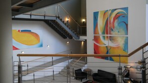 Un hall d’entrée spacieux avec un escalier, une grande peinture abstraite et un coin salon.
