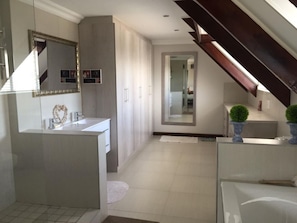 A modern bathroom with a large mirror, a vanity with a heart-shaped decoration, and a separate shower area.