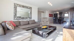A modern living room with a sofa, a glass coffee table, and a dining area in the background. - Quayside 301 by CTHA (Cape Town)
