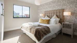 A bedroom with a large bed, two bedside tables, a window, and a ceiling light. - Quayside 301 by CTHA (Cape Town)
