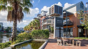 A waterfront property with a brick patio, outdoor seating, and a canal. - Quayside 301 by CTHA (Cape Town)