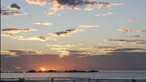 A sunset over a calm sea with a distant landmass.
