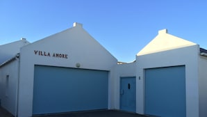 A building with the name "Villa Amore" on the facade, featuring two large blue garage doors and a small door marked with the number 8.