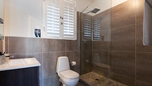 Un baño moderno con inodoro, lavabo y zona de ducha.