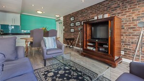 Un salon avec un mur en briques, un téléviseur et un canapé.