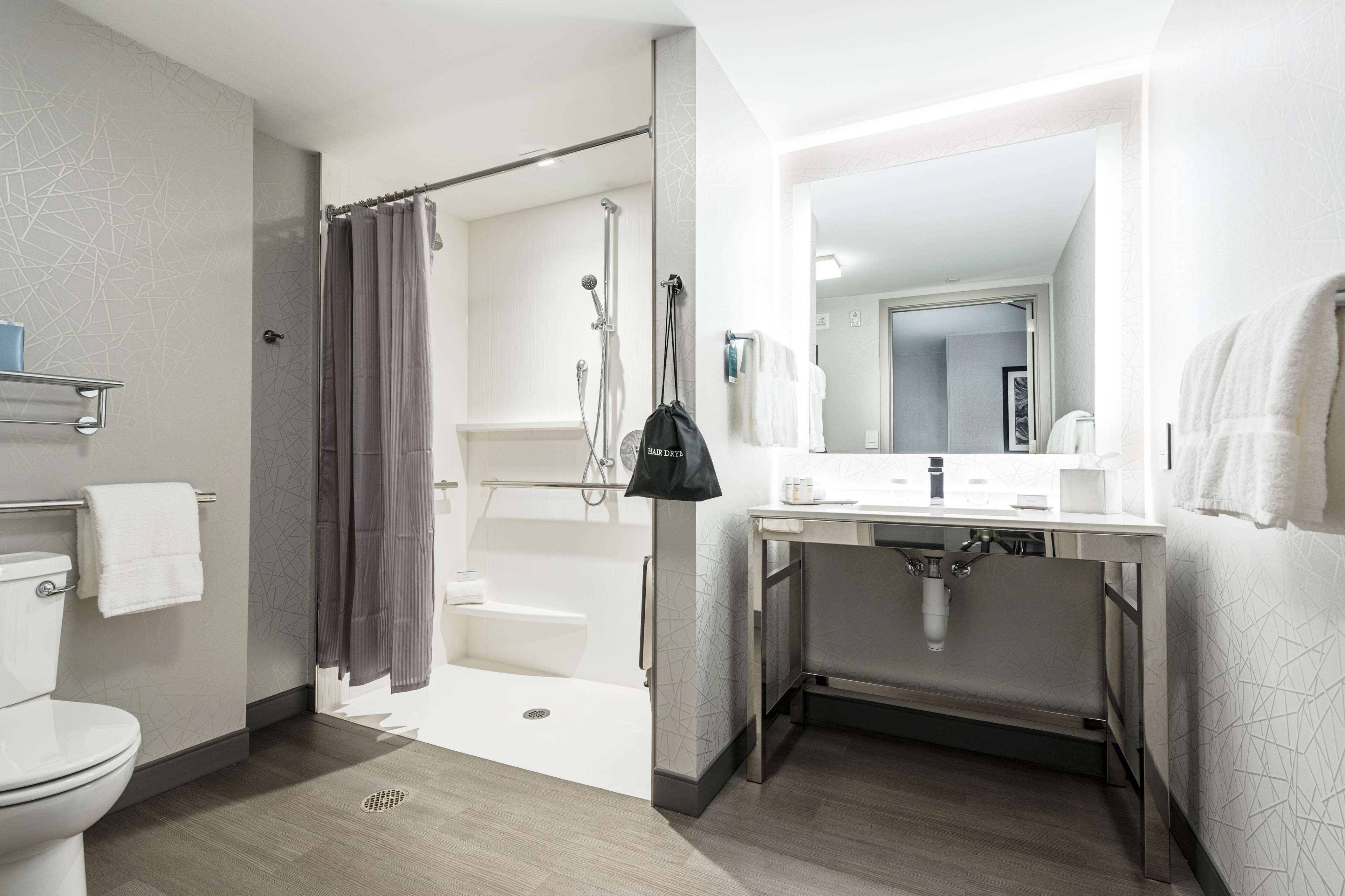 A modern bathroom with a shower, toilet, and sink.