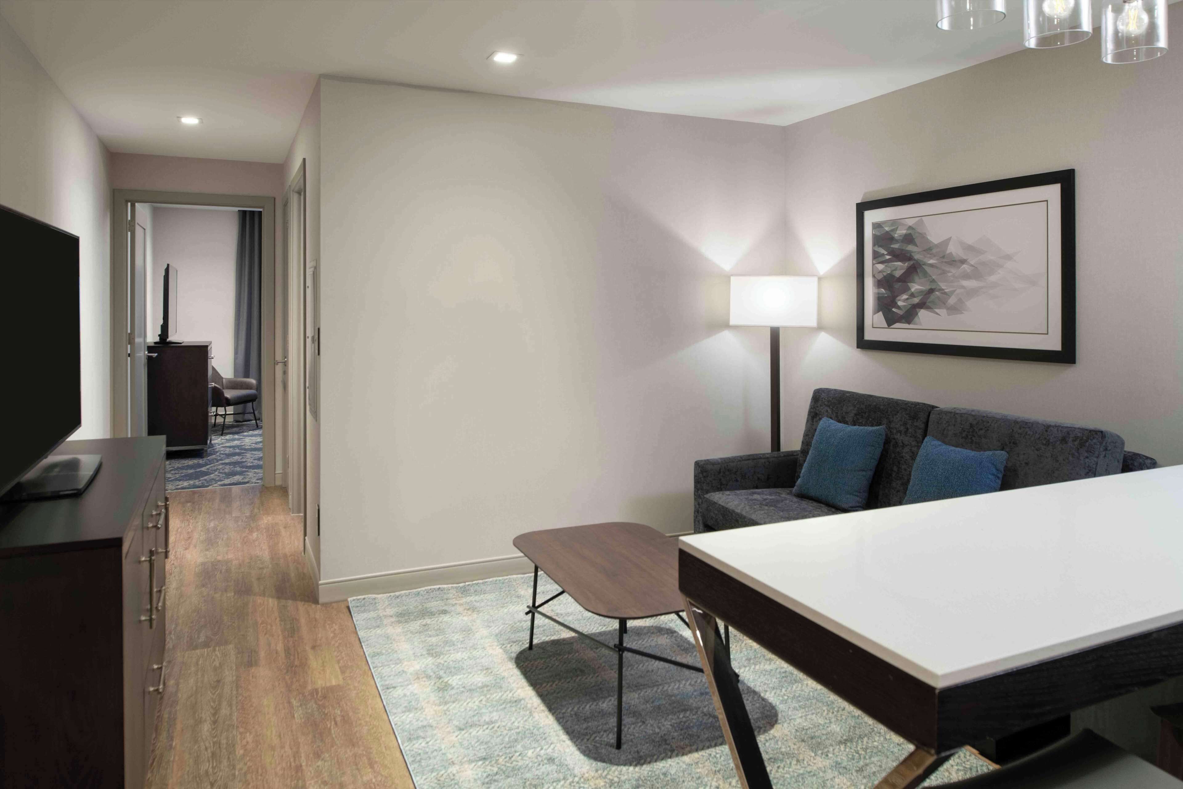 A modern hotel room with a large bed, a desk, a sofa, and a TV.
