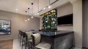 A modern kitchen with a bar area, wooden flooring, and a large window. - Homewood Suites by Hilton Boston Logan Airport Chelsea (Chelsea)