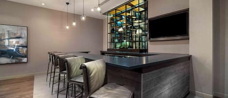 A modern kitchen with a bar area, wooden flooring, and a large window.