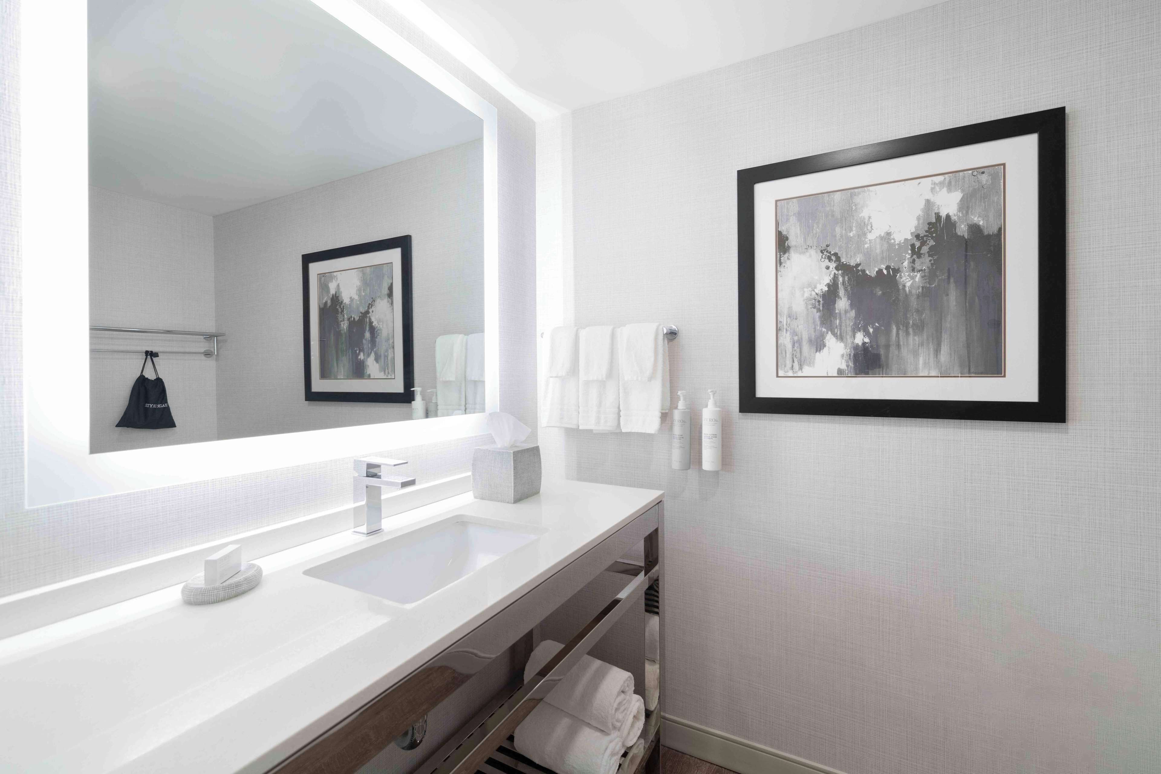 Un bagno moderno con uno specchio grande, due lavabi e un porta asciugamani.
