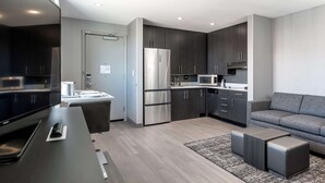 A modern kitchen with dark cabinets, a stainless steel refrigerator, and a microwave. - Homewood Suites by Hilton Boston Logan Airport Chelsea (Chelsea)