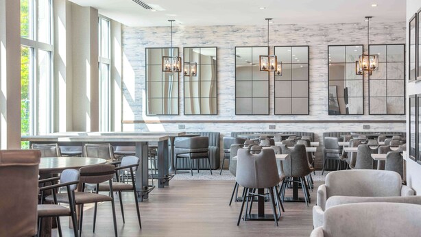 A spacious dining area with high ceilings, large windows, and modern lighting fixtures. - Homewood Suites by Hilton Boston Logan Airport Chelsea (Chelsea)