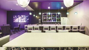 Zona de bar con una barra alargada, diversas opciones de asiento e iluminación colgante.