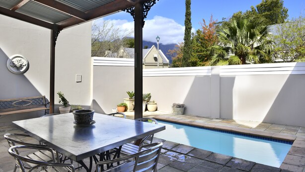 A covered patio with a pool, outdoor seating, and a view of a mountain and trees. - La Gratitude Guest House (Franschhoek)