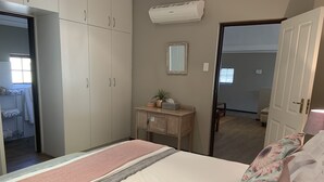 A bedroom with a bed, a bedside table, a wardrobe, and a mirror. - La Gratitude Guest House (Franschhoek)
