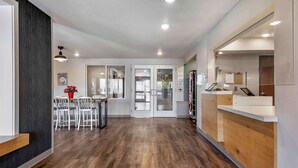A modern hotel lobby with a wooden reception desk, a dining area with white chairs, and a large mirror on the wall. - Extended Stay America Select Suites - Pittsburgh - Cranberry (Cranberry Township)