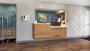 A reception desk with a wooden finish, a digital display, and a framed photograph on the wall. - Extended Stay America Select Suites - Pittsburgh - Cranberry (Cranberry Township)