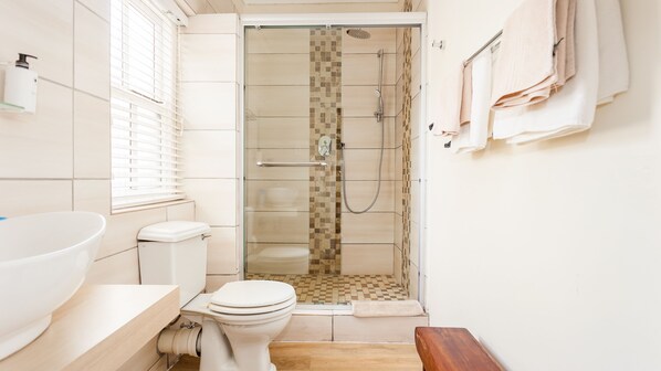 Un baño con inodoro, lavamanos y zona de ducha.