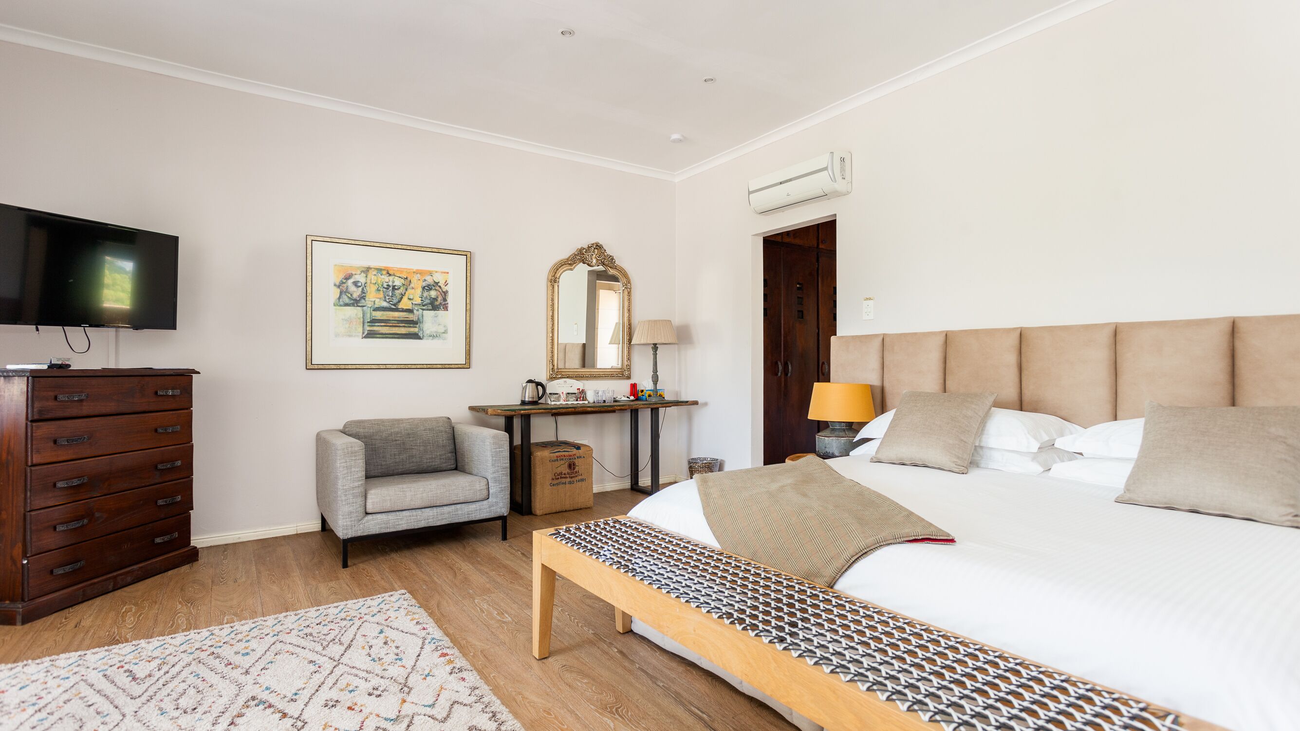 Une chambre d’hôtel comprenant un lit, une télévision, un bureau avec une chaise, une commode et un grand miroir.
