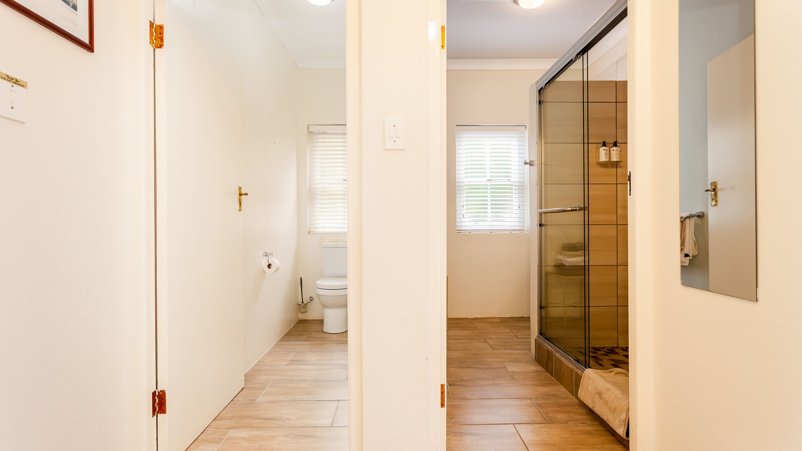 Un bagno con il water, una doccia con porta in vetro e un portascopevoli.