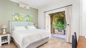 A bedroom with a bed, nightstands, a window with curtains, and a view of greenery outside. - Lady Loch Country House (Wellington)