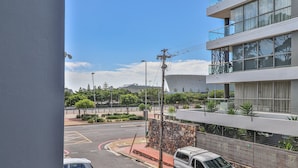 A modern building with a stone facade, a parking area with a white car, and a clear blue sky. - Eaton Square 2 by CTHA (Cape Town)