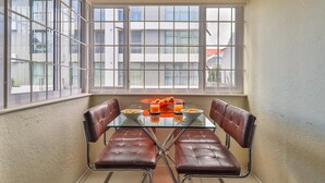 A dining area with a glass table and brown leather chairs, a bowl of fruit, and a glass of orange juice. - Eaton Square 2 by CTHA (Cape Town)