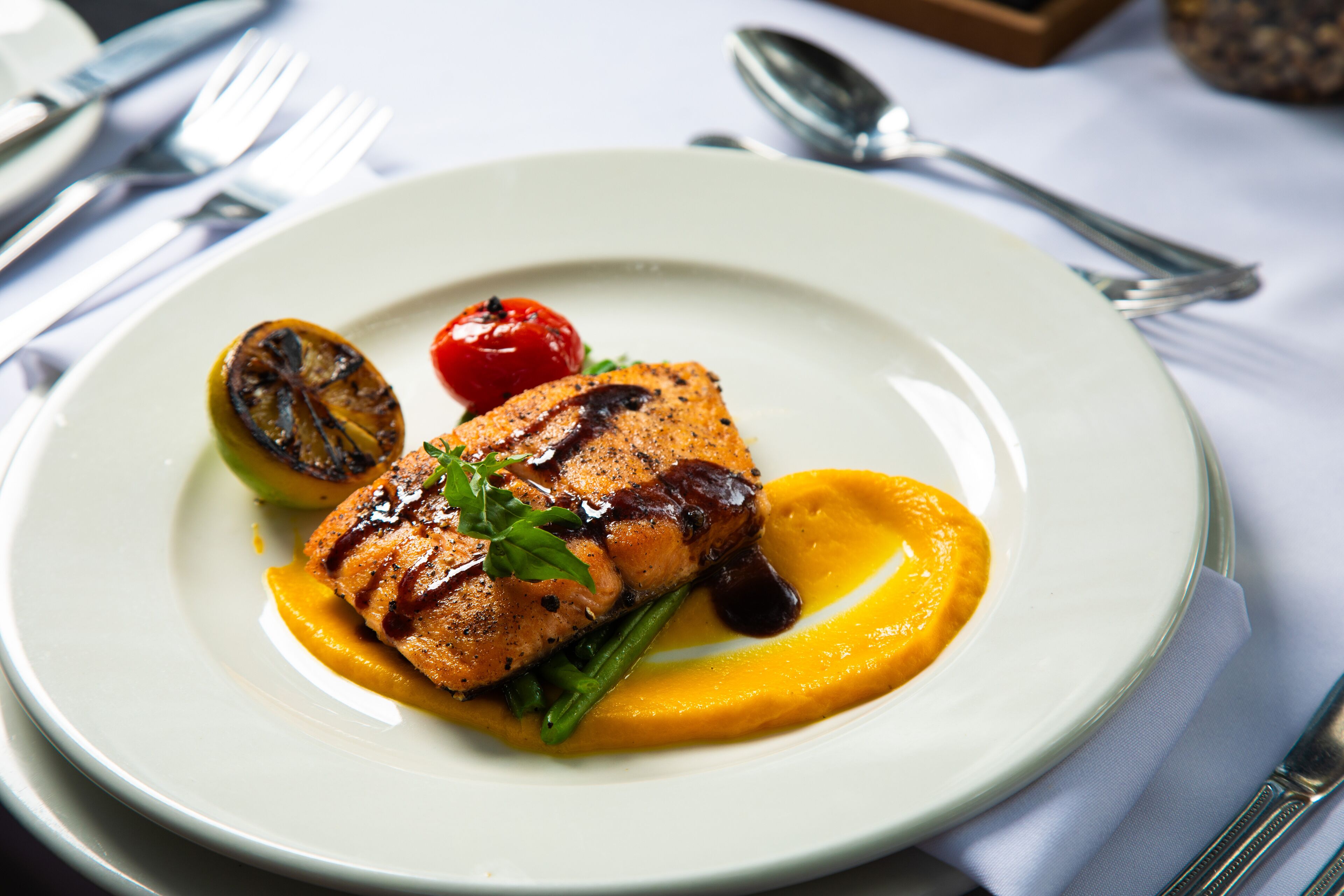 Une assiette de saumon grillé, accompagnée d’une portion de purée de pommes de terre et de légumes grillés.