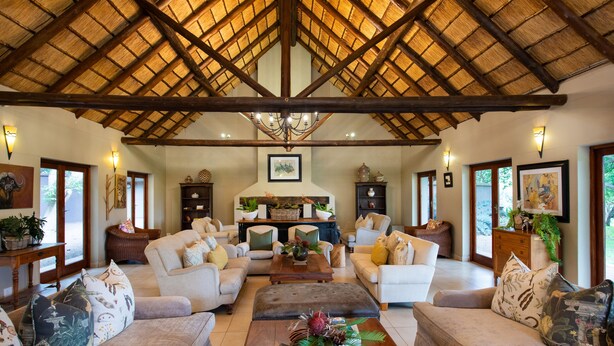 A spacious living room with a high wooden ceiling, comfortable seating, and a central coffee table. - Falaza Game Lodge (Hluhluwe)