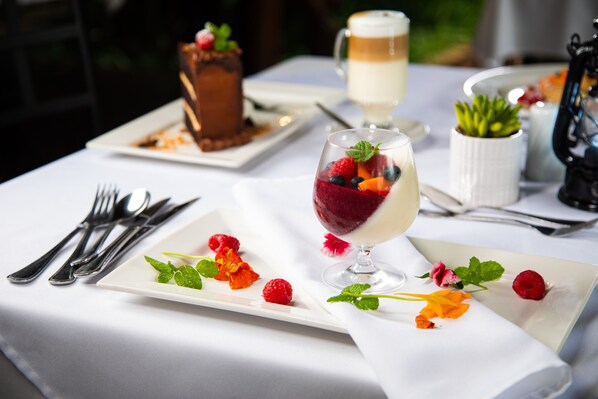 A table set for a meal with a dessert, a glass of beverage, and a small potted plant.