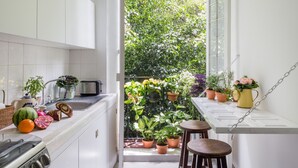 Uma cozinha pequena com armários brancos, pia e janela com vista para um jardim exuberante.