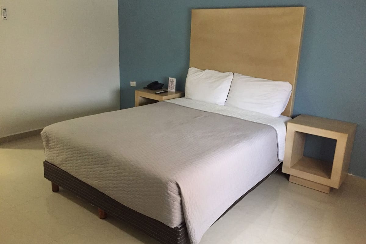 A bed with a headboard, a bedside table, and a nightstand.